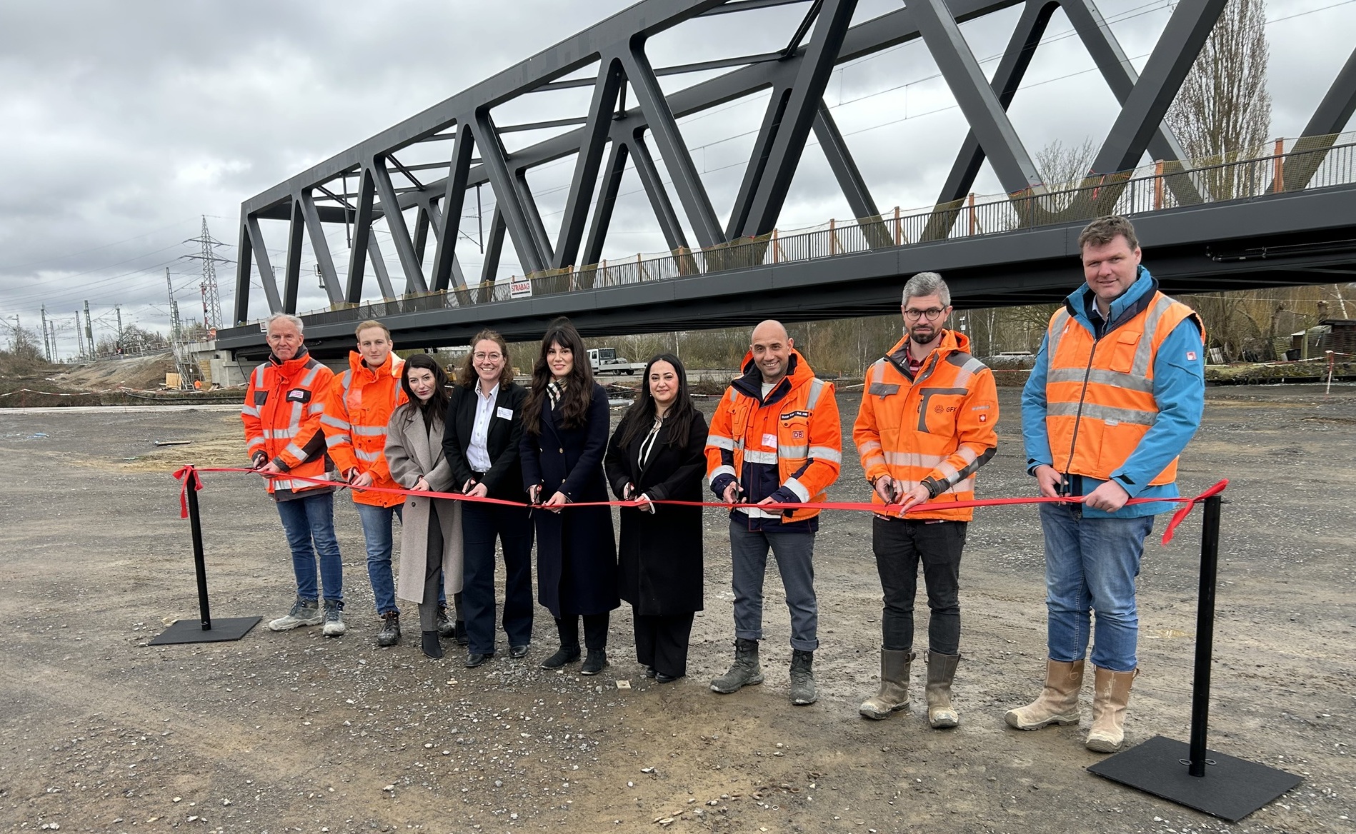 Symbolischer Festakt zur Inbetriebnahme der Brücke mit Detlev Brandes (Bauleiter), Yannick Massafra, Asuman Kisakaya (Projektleiterin), Petra Eder, Tugce Sezgin (Leiterin Konstruktiver Ingenieurbau Hannover), Lizan Hussen (Teilprojektleiterin), Burak Kor, Sergej Stieben und Marco Geisler (v. l. n. r.) (März 2026) [Quelle: DB InfraGO AG, 8]